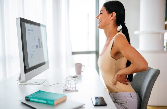 Overworked woman with back pain in office with bad posture
