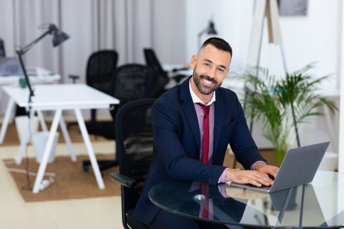 Professional man typing on laptop at modern office desk during work hours